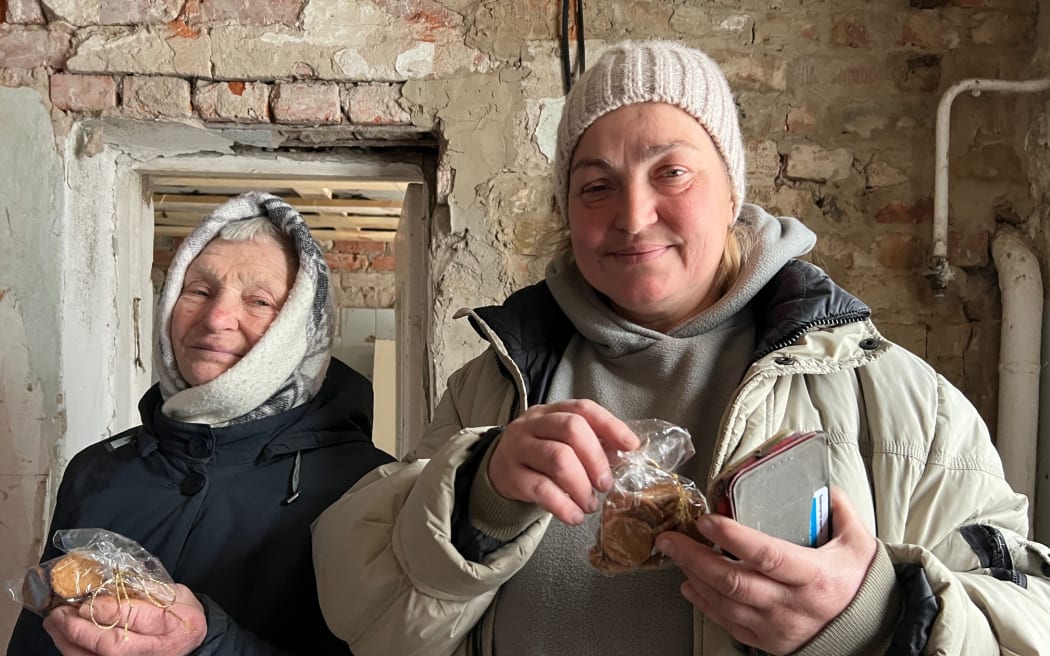 Lludmila and her daughter Natalia holding biscuits baked by David Hancock in Eltham, Taranaki. This photo was taken in 86-year-old Lludmila’s home in Chernihiv Ukraine. She hid in its cellar as missile strikes landed around her before being evacuated in the middle of the night. When she returned one side of the house had been blown off. They returned to the house each day to pick up the bricks and one by one rebuild it.