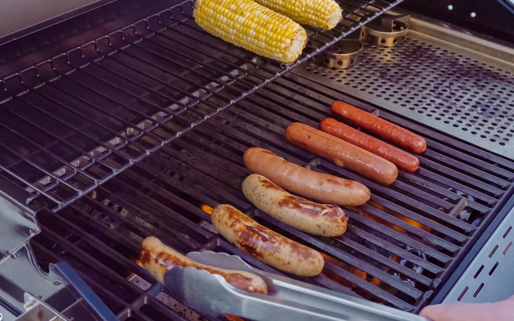 Cooking hot dogs and bratwurst on outdoor gas grill in the Summer.