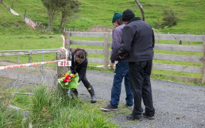 People place flowers at the entrance to the Kinohaku property where three bodies were found, including that of Ross Bremner.
