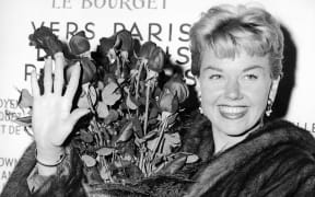 American actress and singer Doris Day holds a bouquet of roses at Le Bourget Airport in Paris in 1955 after flying in from London.