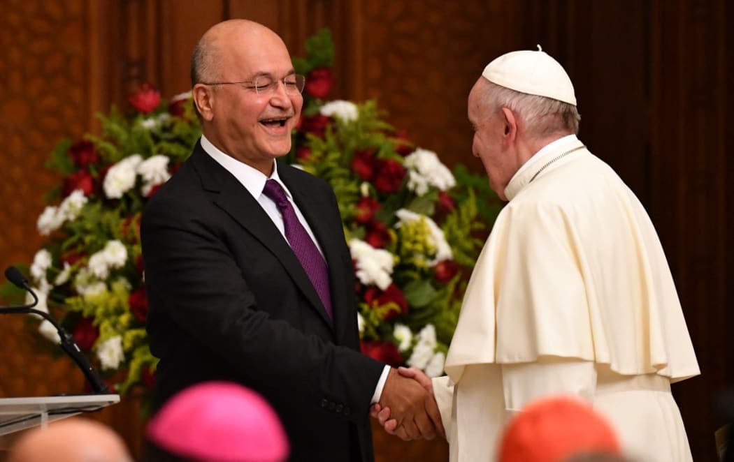 Pope Francis shakes hands with Iraqi President Barham Saleh at the presidential palace in Baghdad on March 5, 2021 on the first papal visit to Iraq.