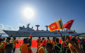 Workers wave China's and Sri Lanka's national flags upon the arrival of China's research and survey vessel, the Yuan Wang 5 at Hambantota port, Sri Lanka on 16 August, 2022.