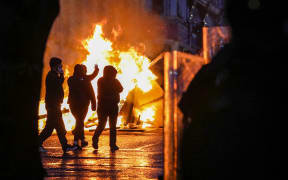Protestors walk past a fire lit in a street of Ballymena, Northern Ireland, during an anti-immigration demonstration.
