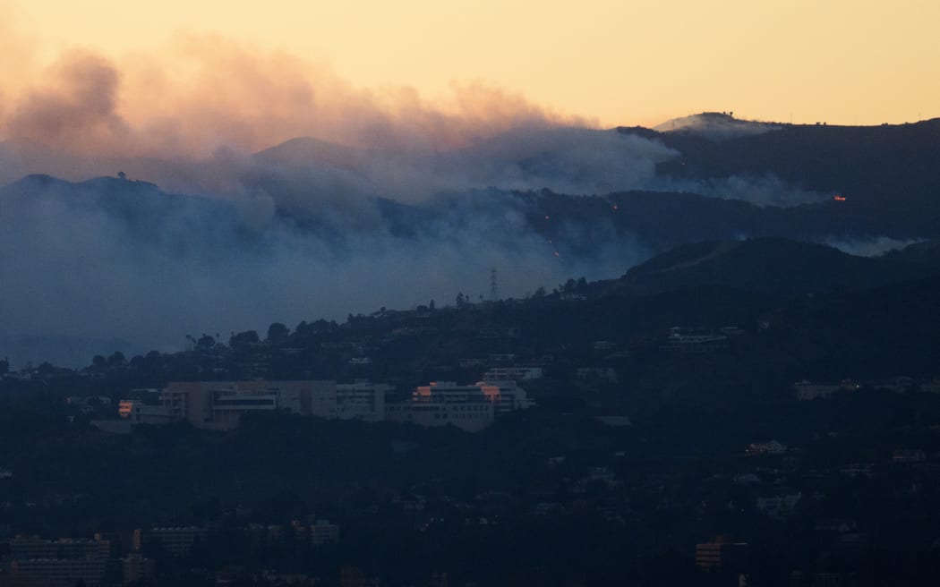 An aerial image shows fire and smoke behind the Getty Center Museum from wildfires, including the Palisades Fire, at sunset over Los Angeles, California, on January 8, 2025. - At least five people are now known to have died in wildfires raging around Los Angeles, with more deaths feared, law enforcement said January 8, as terrifying blazes leveled whole streets, torching cars and houses in minutes.
More than 1,000 buildings have burned in multiple wildfires that have erupted around America's second biggest city, forcing tens of thousands of people from their homes. (Photo by Patrick T. Fallon / AFP)