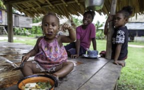 A girl eats vegetable broth in Guadalcanal, Solomon Islands.