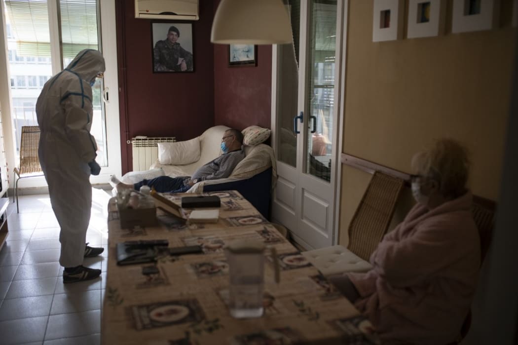 Healthcare worker wearing a protective suit, visits a patient at his home in Barcelona. This week Spain has confirmed a slowdown in the pandemic, according to figures released