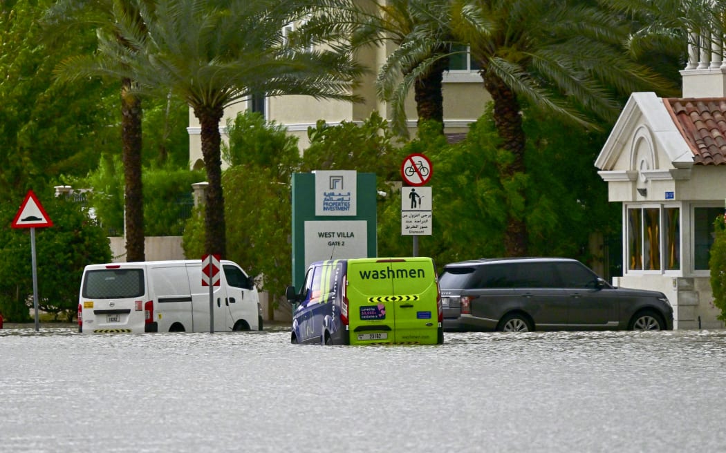 Vehicles are stranded on a flooded street following torrential rain in the Gulf Emirate of Dubai on April 16, 2024. Torrential rains and high winds lashed parts of the Gulf on April 16, as the death toll from storms in Oman rose to 18, many of them children. Flights were cancelled in Dubai, the region's financial hub, while schools were shut in the United Arab Emirates and Bahrain. (Photo by Giuseppe CACACE / AFP)