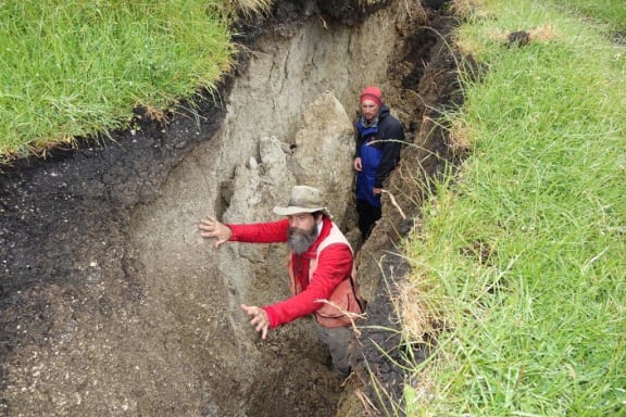 Two geologists standing in a trench