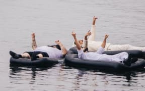 Members of IA and Rei floating in a river on airbeds