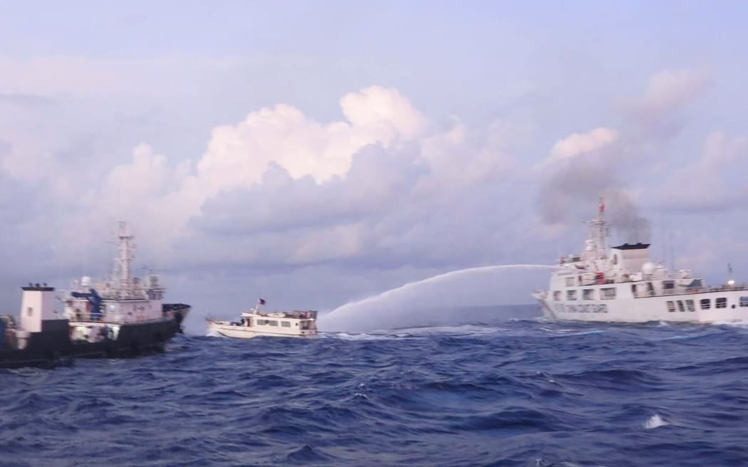 This handout photo taken and released on December 10, 2023 by the Philippine Coast Guard (PCG) shows a China Coast Guard vessel (R) using water cannon against the M/L Kalayaan chartered supply boat (C) during a mission to deliver provisions at Second Thomas Shoal in disputed waters of the South China Sea. A Philippine boat was "rammed" by a Chinese coast guard ship during a resupply mission on December 10, the Philippine coast guard said, in the latest such confrontation in the disputed South China Sea. The Philippine Coast Guard also said a Chinese ship "water cannoned" three Philippine vessels involved in the resupply mission, causing "serious engine damage" to one of the boats. (Photo by Handout / Philippine Coast Guard (PCG) / AFP) / RESTRICTED TO EDITORIAL USE - MANDATORY CREDIT "AFP PHOTO /  PHILIPPINE COAST GUARD (PCG)" - NO MARKETING - NO ADVERTISING CAMPAIGNS - DISTRIBUTED AS A SERVICE TO CLIENTS
