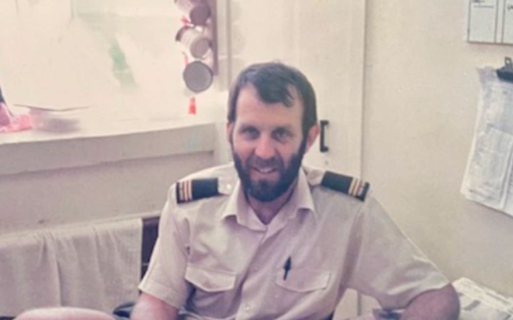 Archival image of Mark Anthony as a prison officer seated at a desk and holding papers or documents.