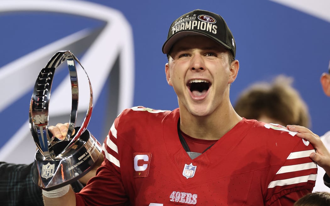 Brock Purdy of the San Francisco 49ers reacts as he holds the George Halas Trophy after defeating the Detroit Lions 34-31 in the NFC Championship Game.