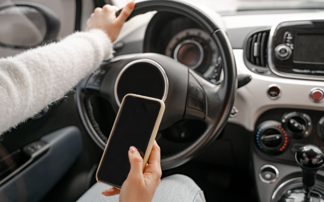 Woman hand hold and use mobile phone in personal auto. Close up view. Modern luxury automobile. Concept of driving car