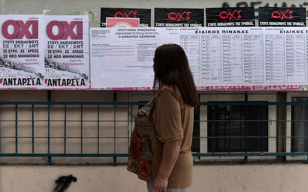 A woman looks at placards reading 'No' and voting information outside a polling station in Athens.