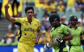 Pakistan's batsman Sarfraz Ahmed (C) walks off the field as Australia's paceman Mitchell Starc (L) celebrates his dismissal.