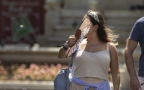 A woman, using a fan, is seen as heatwave hits London.