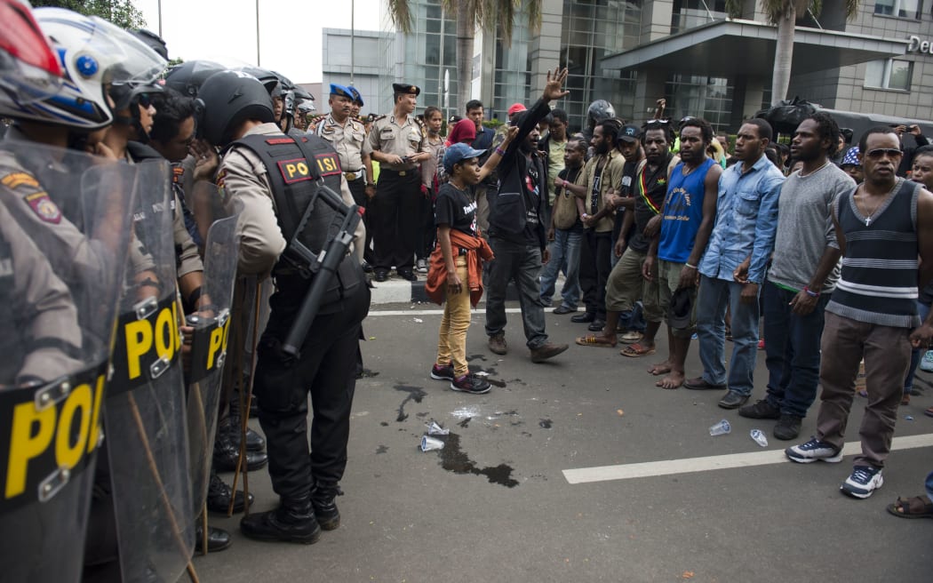 Papuan pro-independence demonstrators stage a protest while police (L) armed with tear gas guns take position in Jakarta on December 1, 2015, before police fired tear gas at a hundreds-strong crowd hurling rocks during a protest against Indonesian rule over the eastern region of Papua.