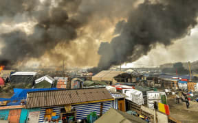 Smoke rises from a fire over the "Jungle" migrant camp in Calais, northern France, on October 26, 2016, during a massive operation to clear the squalid settlement where 6,000-8,000 people have been living in dire conditions.
