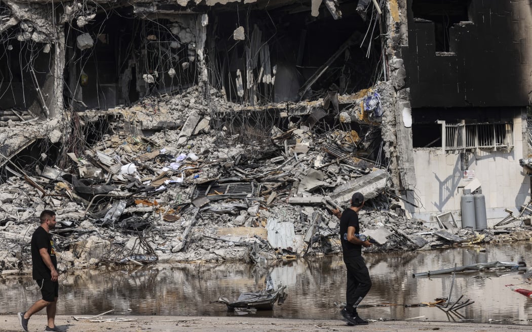 People walk past an Israeli police station in Sderot after it was damaged during battles to dislodge Hamas militants who were stationed inside, on October 8, 2023.