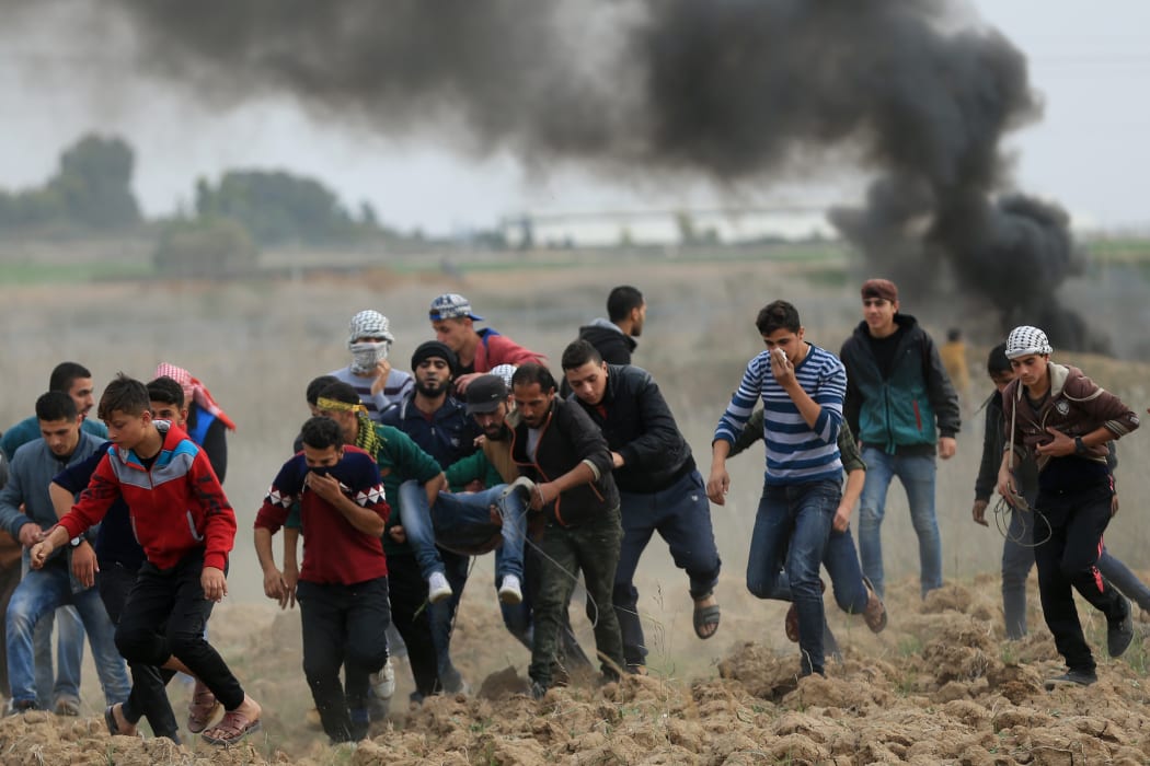 Palestinian protesters carry a wounded comrade during clashes with Israeli soldiers near the border fence east of Gaza City on December 22, 2017.