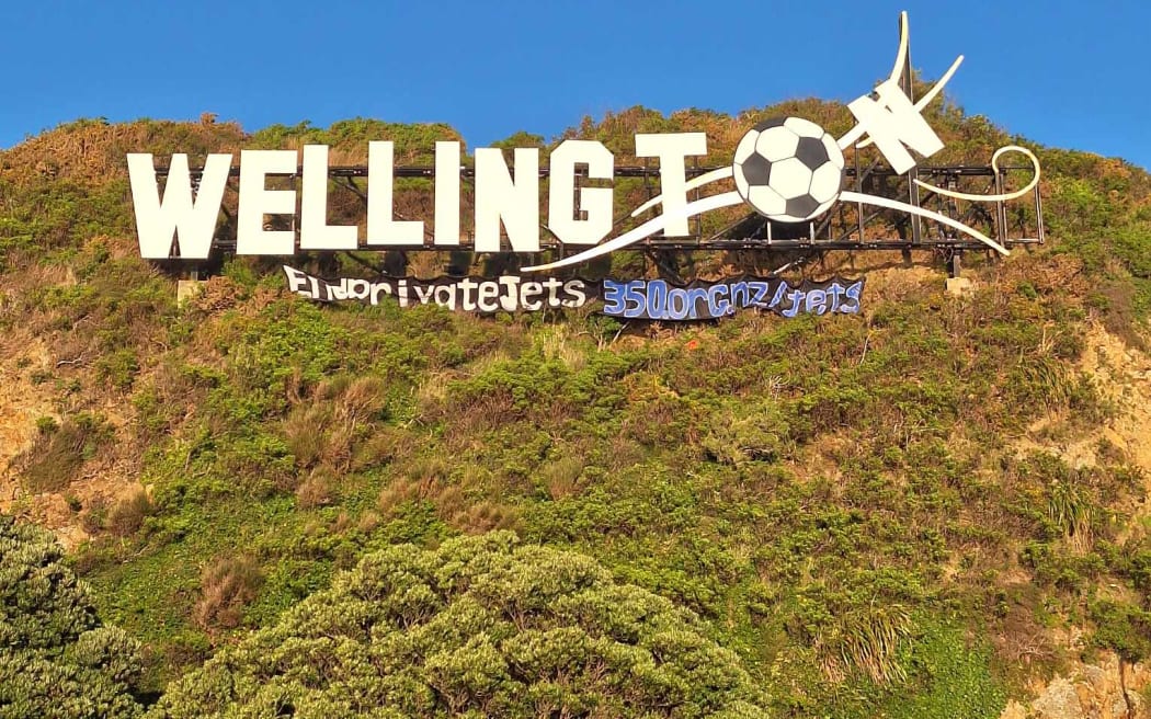 An image of the 'End Private Jets' banner underneath the Wellington sign.