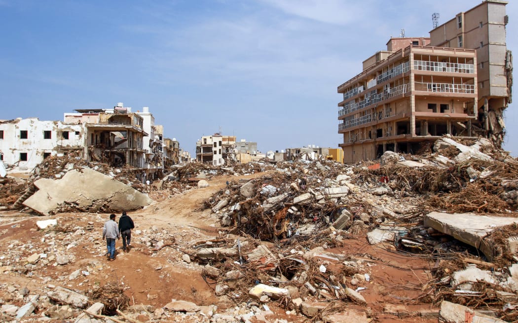 Men walk past debris of buildings caused by flash floods in Derna, eastern Libya, on September 11, 2023.
