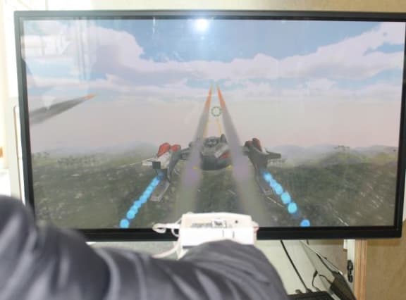 View along the arm of a gamer wearing the haptic feedback glove as he plays the flight simultor