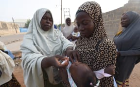 A volunteer health worker tries to immunise a child during a vaccination campaign in north-west Nigeria