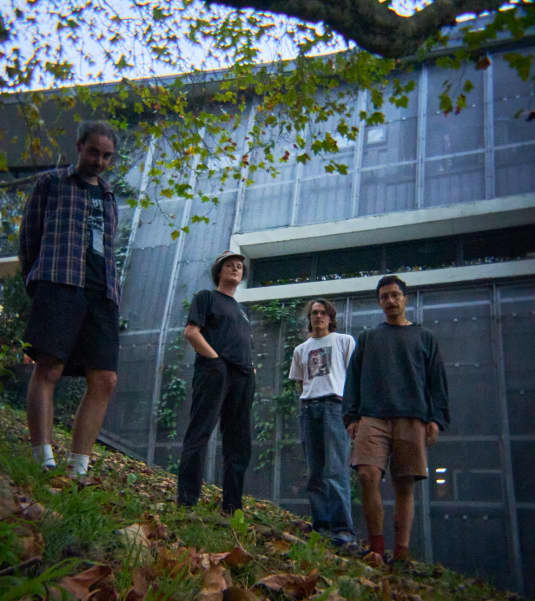 Four people stand on a slope in front of a building.