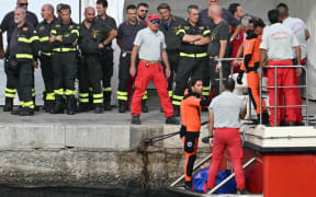 Divers of the Vigili del Fuoco, the Italian Corps. of Firefighters arrive in Porticello harbor near Palermo, with a third body at the back of the boat on August 21, 2024, two days after the British-flagged luxury yacht Bayesian sank. Divers searching for six missing people following the sinking of a superyacht off Sicily in a storm have found four bodies, a source close to the search told AFP. The Bayesian, which had 22 people aboard including 10 crew, was anchored some 700 metres from port before dawn when it was struck by a waterspout. Among the six missing were UK tech entrepreneur Mike Lynch and his 18-year-old daughter Hannah, and Jonathan Bloomer, the chair of Morgan Stanley International, and his wife Judy. (Photo by Alberto PIZZOLI / AFP)