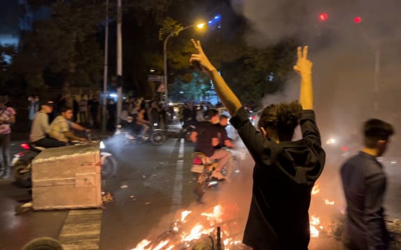 A picture obtained by AFP outside Iran shows shows a demonstrator raising his arms and makes the victory sign during a protest for Mahsa Amini, a woman who died after being arrested by the Islamic republic's "morality police", in Tehran on September 19, 2022.