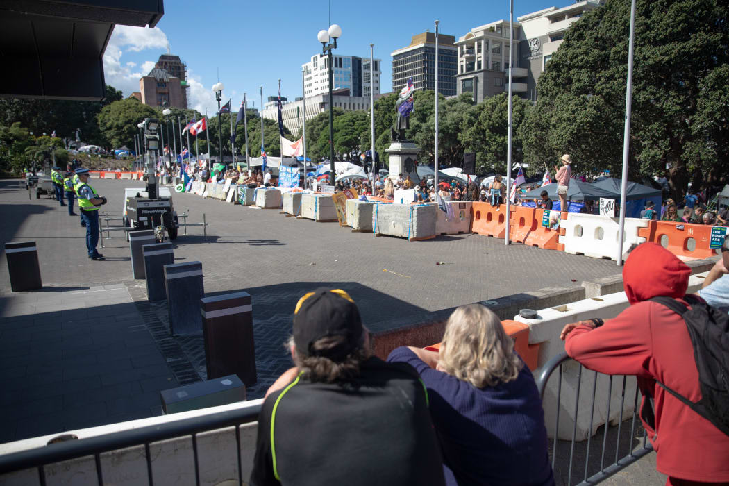 Anti-vaccine, anti-mandate protest in Wellington on Parliament grounds on 16 February 2022. Police standing on forecourt.