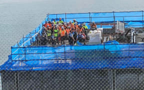 Police and construction workers can be seen on the roof of a construction site in Auckland's downtown CBD on 20 July, 2023 following a serious shooting incident.