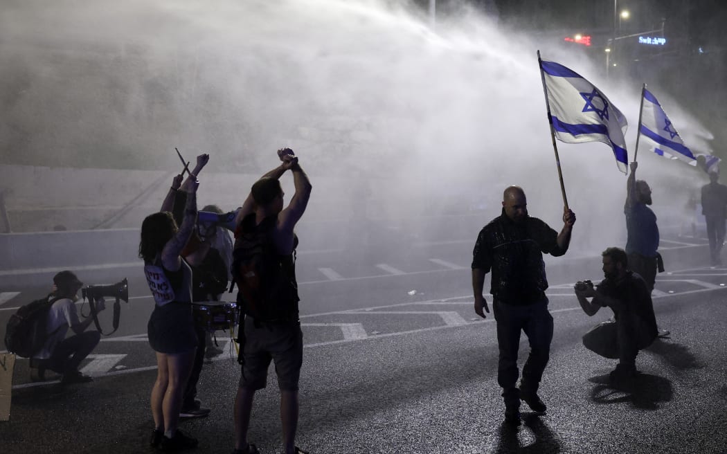 Israeli police spray protesters with water as they block a road during a gathering by relatives of Israeli hostages held in Gaza since the October 7 attacks by Hamas militants, in front of the Defense Ministry in the Israeli coastal city of Tel Aviv, on March 30, 2024, amid the ongoing conflict in the Gaza Strip between Israel and the Palestinian militant Hamas movement. (Photo by JACK GUEZ / AFP)