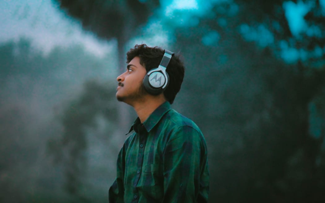 A person looking into the distance wearing over-ear headphones.