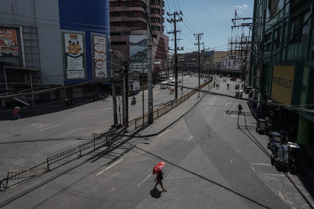 A woman with umbrella walks along a deserted street at Divisoria public market in Manila, Philippines on April 01, 2020.