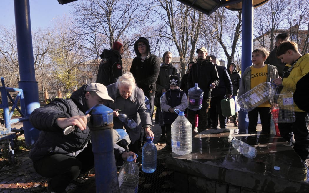 Kyiv residents fill plastic containers and bottles at a water pump in a park on 31 October 2022 after what Ukrainian officials called another "massive" Russian missile attack on energy facilities.