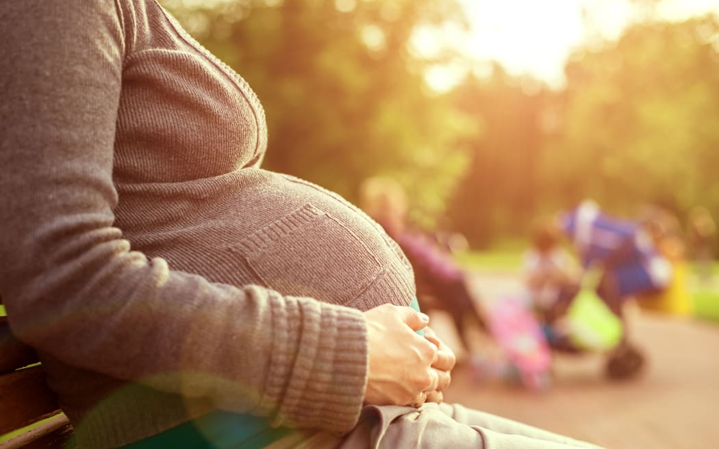 Pregnant woman sitting on a bench.