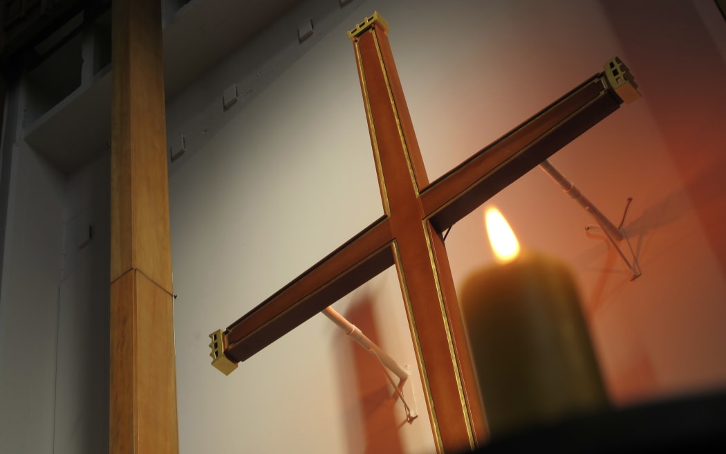 Candle and cross on wall behind high altar