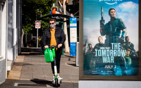 A man rides his scooter on a deserted street pavement in Brisbane on June 30, 2021, as the city falls quiet from a lockdown with Australia battling outbreaks of the highly contagious Delta variant of Covid-19.