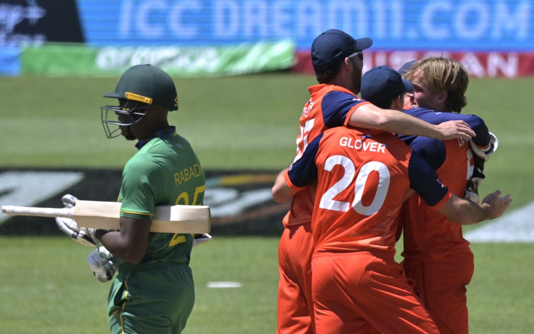 Netherlands' players celebrate their win as South Africa's Kagiso Rabada (L) looks on during the ICC men's Twenty20 World Cup 2022 cricket match between Netherlands and South Africa at Adelaide Oval on November 6, 2022 in Adelaide. (Photo by Brenton EDWARDS / AFP) / -- IMAGE RESTRICTED TO EDITORIAL USE - STRICTLY NO COMMERCIAL USE --