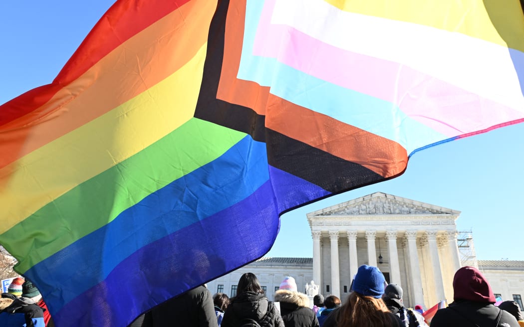 People hold flags outside the US Supreme Court on December 4, 2024 in Washington, DC, during oral argument on whether states can ban certain gender transition medical treatments for young people. - The case was brought by three transgender teens, their parents and a doctor who are seeking to ensure health-care access they say is critical. (Photo by ROBERTO SCHMIDT / AFP)