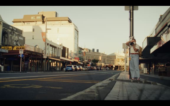 Becki Moss taking photos on Karangahape Road bathed in the afternoon light