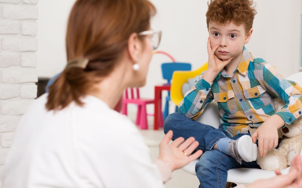 Stock image representing school psychologist talking to young boy.