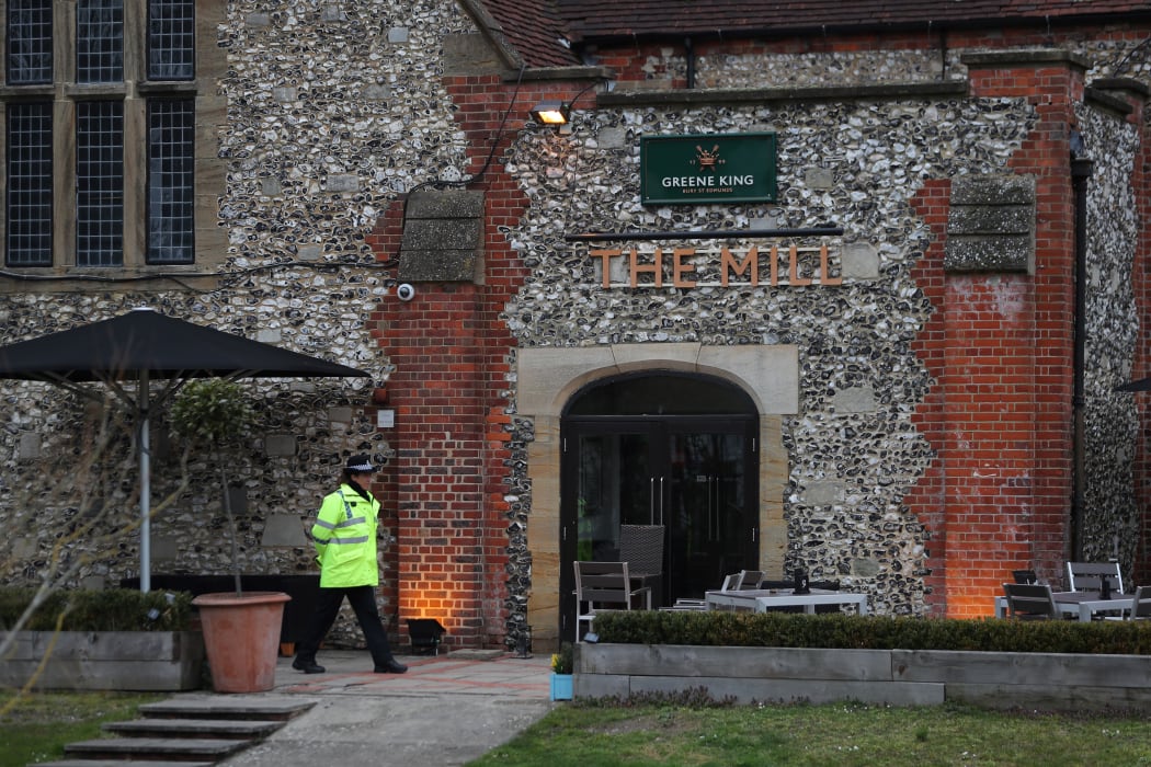 A police officer stands in front of The Mill pub in Salisbury, southern England. Diners are being told to wash their possessions.