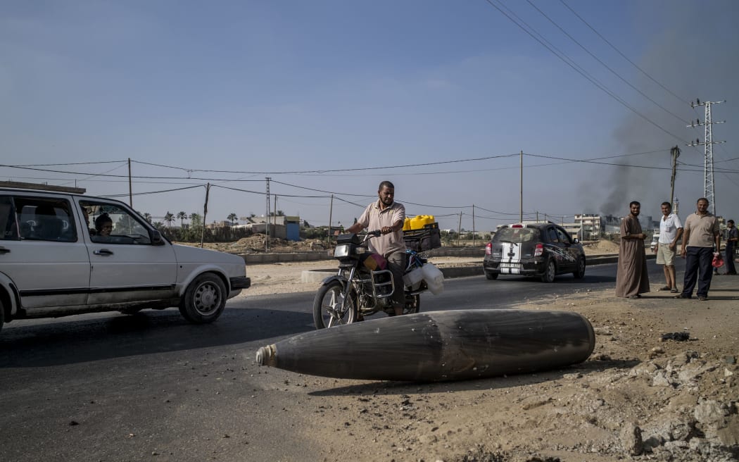 Palestinian onlookers pause to inspect an Israeli army bomb laying unexploded on the road that links northern and southern Gaza.