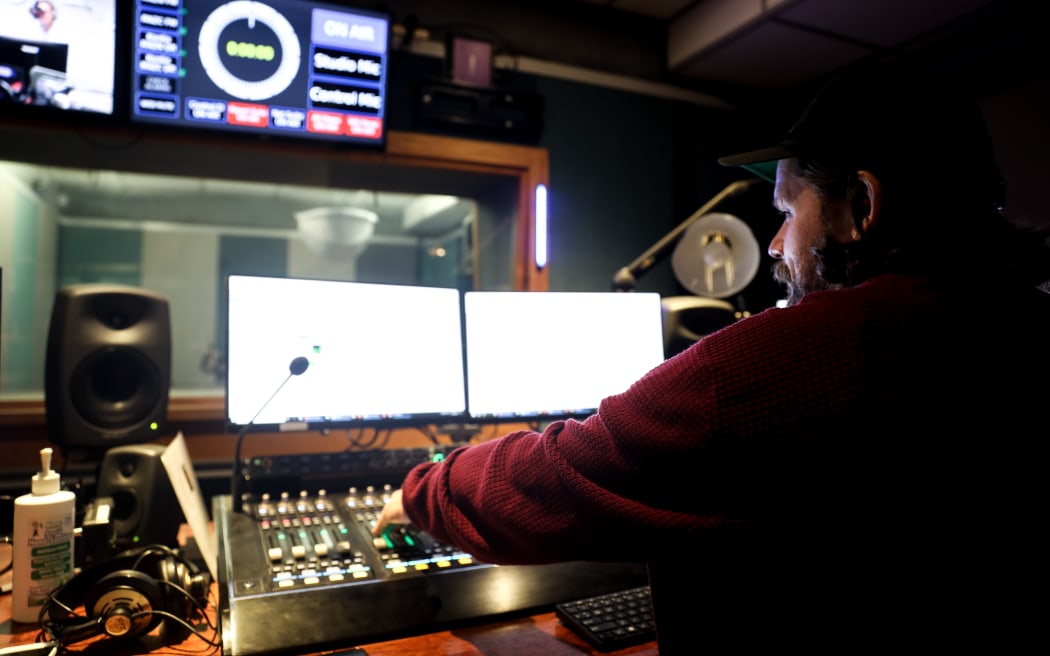 A man sitting behind a radio control desk.