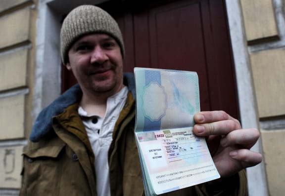Anthony Perrett shows his passport with a Russian transit visa.