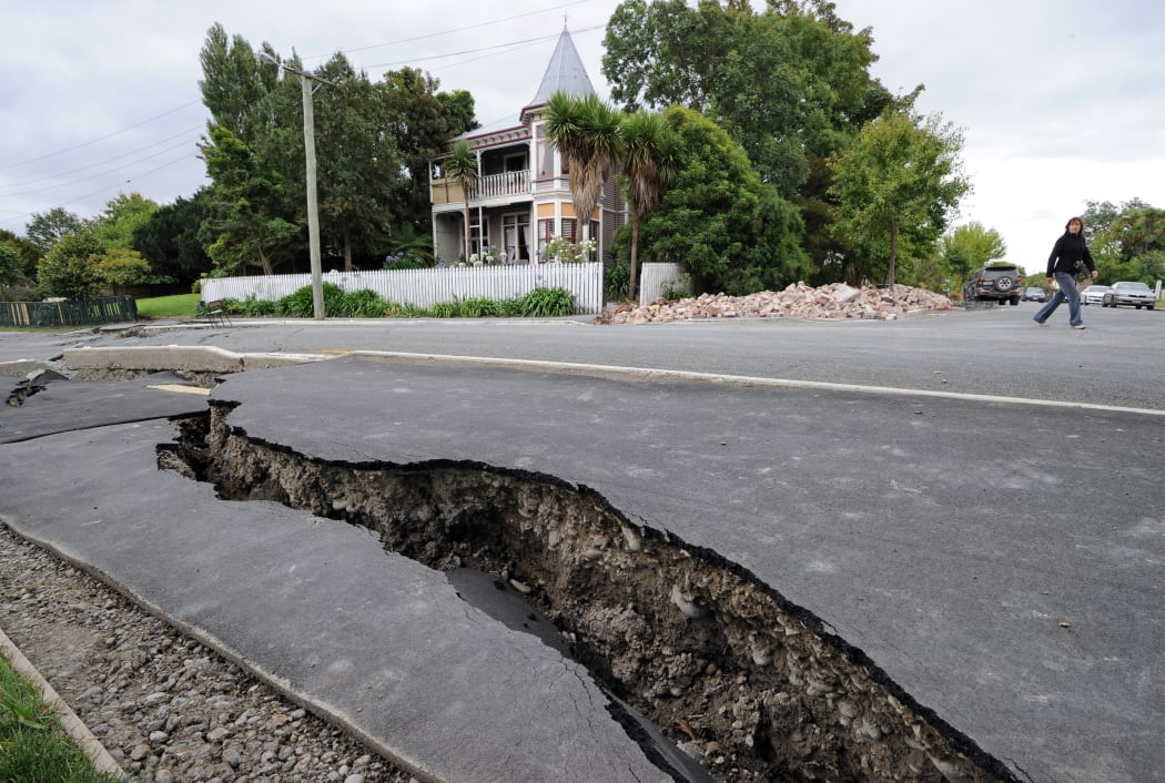 A woman walks across a broken street in the days following the fatal February 22 earthquake.