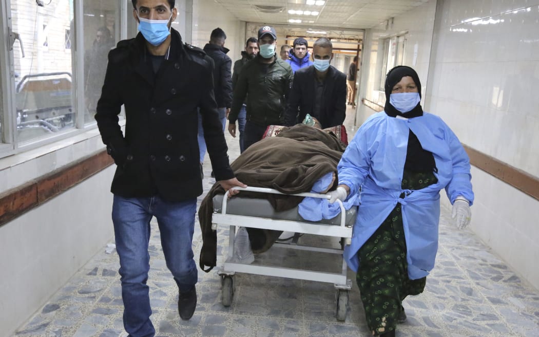 An injured man is rushed to the emergency ward of a hospital following a twin suicide bombing on a bustling commercial street in the heart of the Iraqi capital Baghdad, on January 21, 2021.